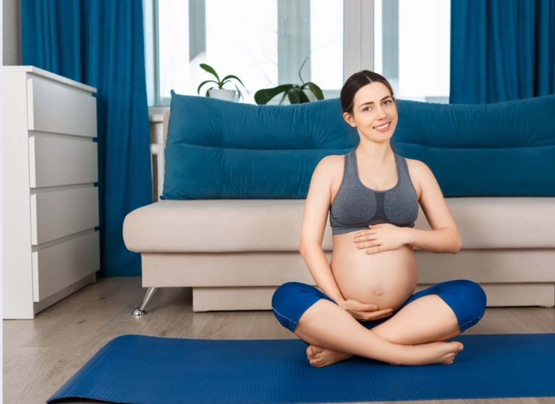 Une future maman pratique des exercices de relaxation à domicile pour se préparer à l'accouchement