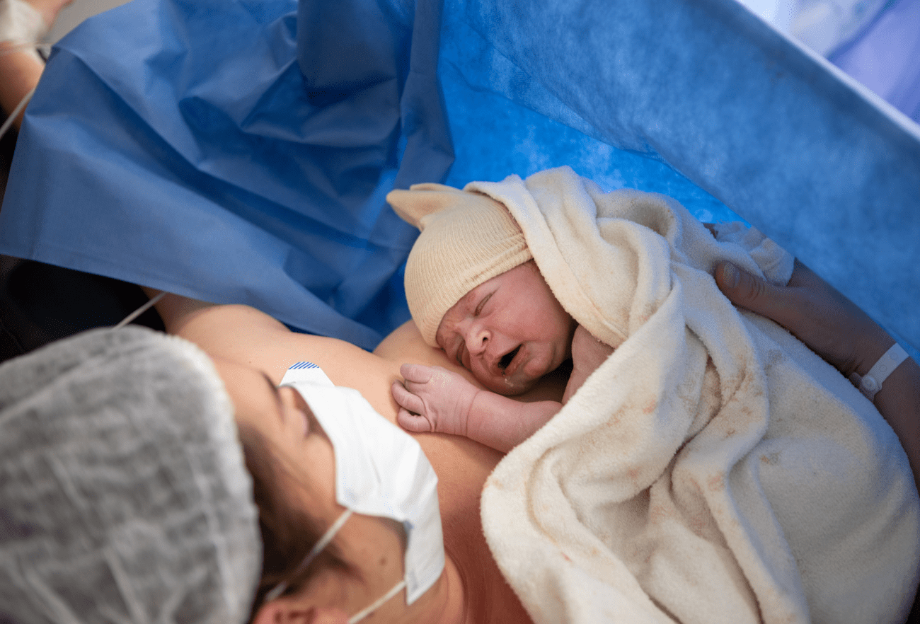 Une maman tient son nouveau-né contre elle juste après la naissance, en salle de naissance