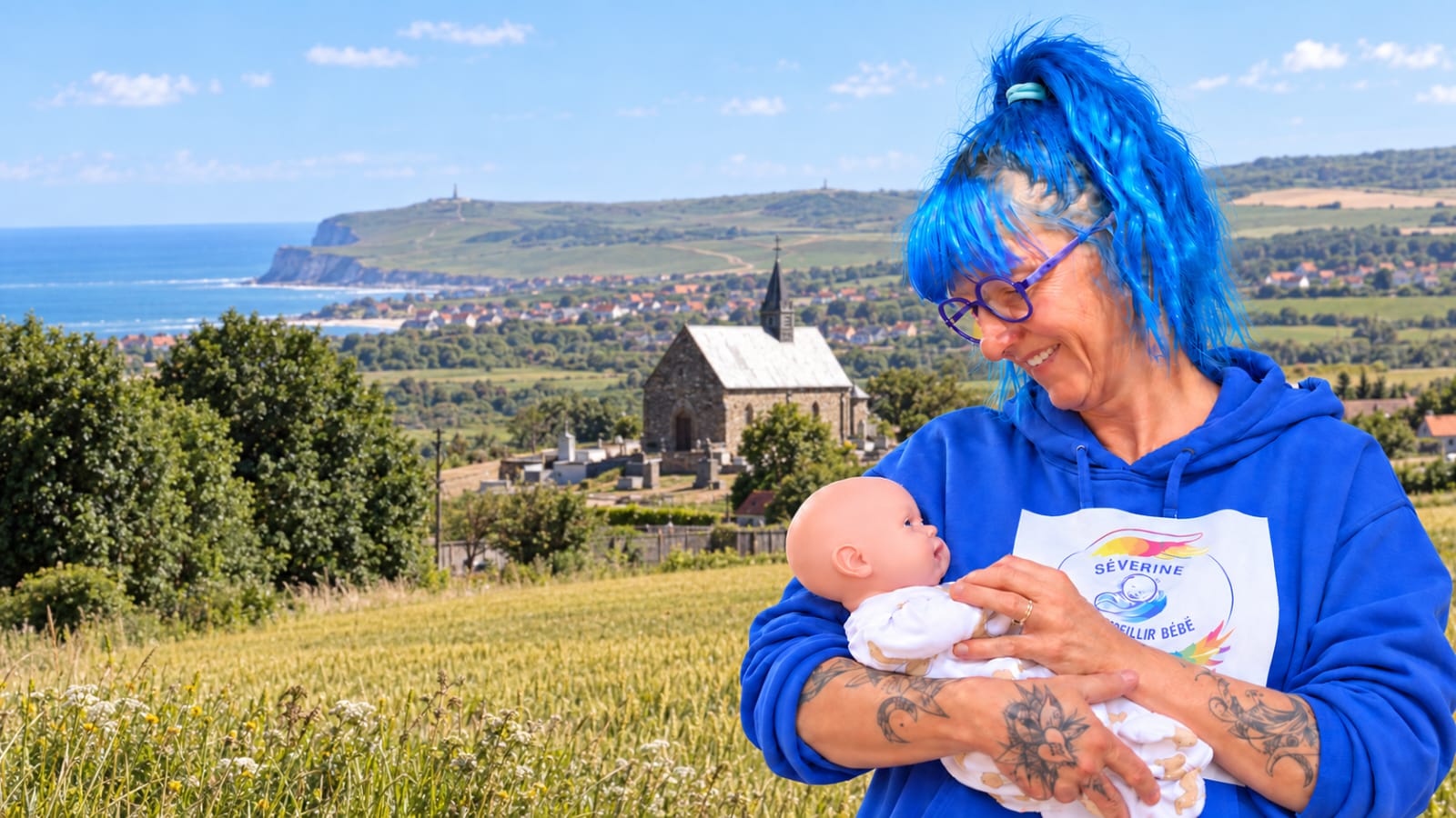 Portrait de Séverine Duflos, accompagnante périnatale sur la terre des 2 cpas , souriante face à la mer, vêtue d’une blouse bleue.